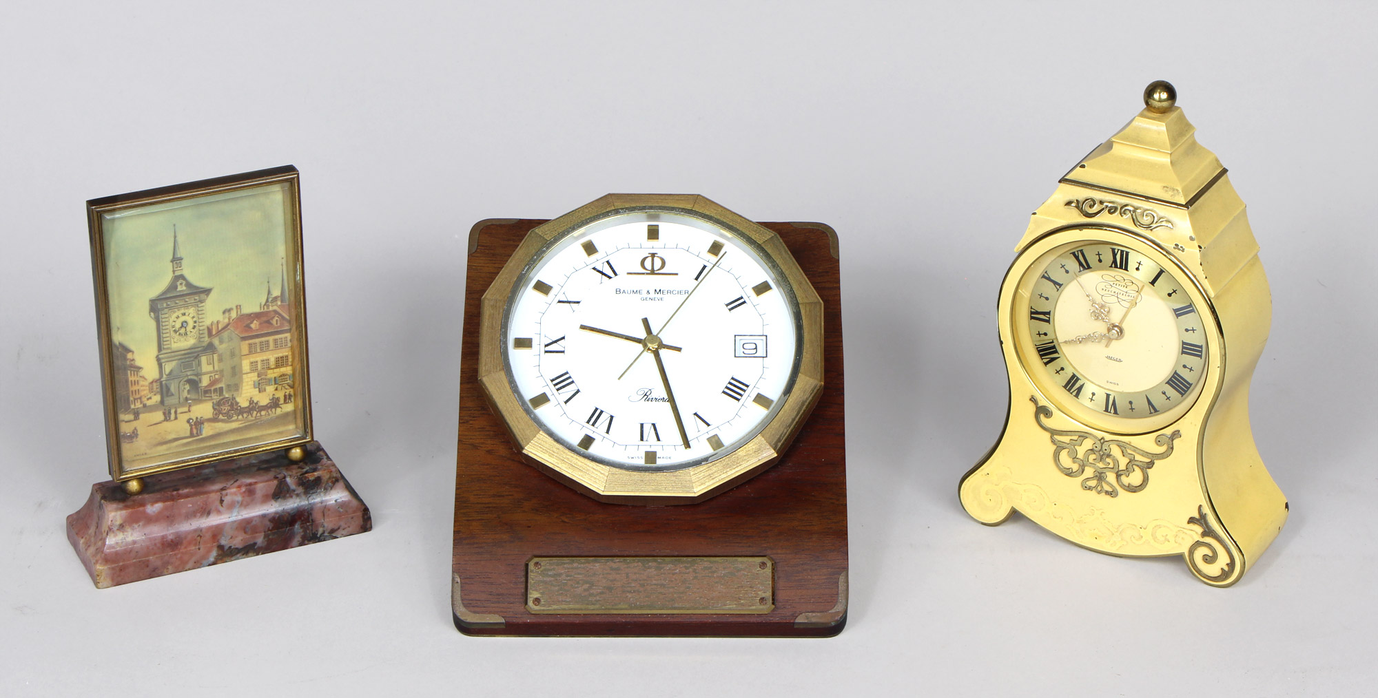 Lotes 926, 927 y 928: 
																		PEQUEÑO RELOJ SUIZO DE APOYO MARCA JUVENIA. 
																		RELOJ DE ESCRITORIO SUIZO MARCA BAUME & MERCIER. 
																		RELOJ DE APOYO CON ALARMA MUSICAL JAEGER LE COULTRE.