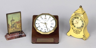 Lotes 926, 927 y 928: 
																		PEQUEÑO RELOJ SUIZO DE APOYO MARCA JUVENIA. 
																		RELOJ DE ESCRITORIO SUIZO MARCA BAUME & MERCIER. 
																		RELOJ DE APOYO CON ALARMA MUSICAL JAEGER LE COULTRE.